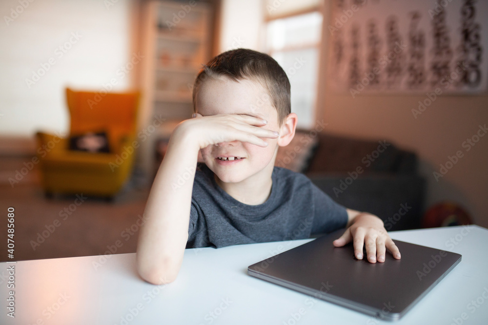 boy covering his eyes while looking at a laptop boy covering his eyes while looking at a laptop