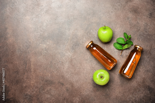 Apple juice in a bottle, green apple and fresh mint leaves on a dark rustic background. Top view, flat lay, copy space.