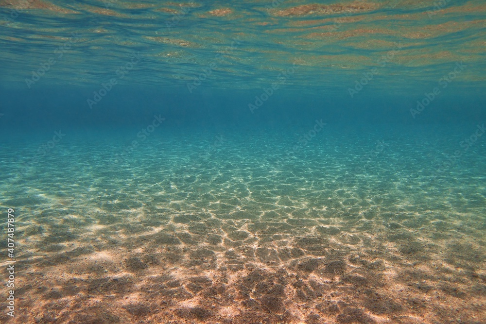 Underwater view, sandy sea bottom and transparent water. Life-giving sunlight underwater.