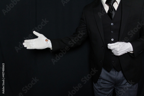 Konstfotografi Black and White Portrait of Butler or Servant in Dark Suit and White Gloves with a Welcoming Gesture
