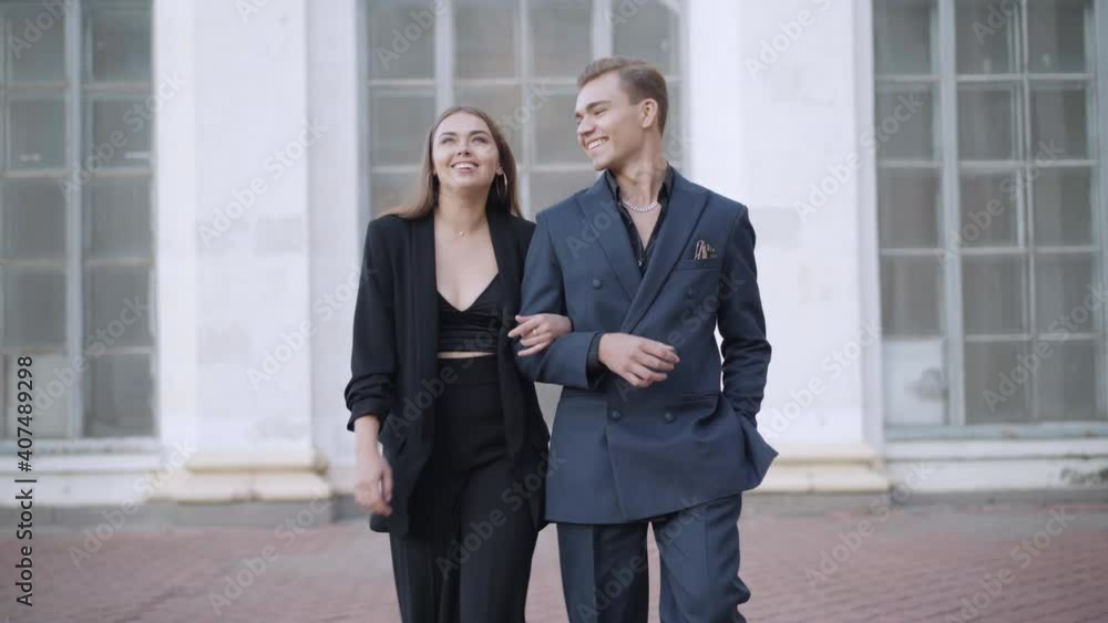 Portrait of positive young Caucasian couple walking and talking in urban city. Smiling joyful handsome man and beautiful woman leaving. Dating and relationship concept. Portrait of positive young Caucasian couple walking and talking in urban city. Smiling joyful handsome man and beautiful woman leaving. Dating and relationship concept.