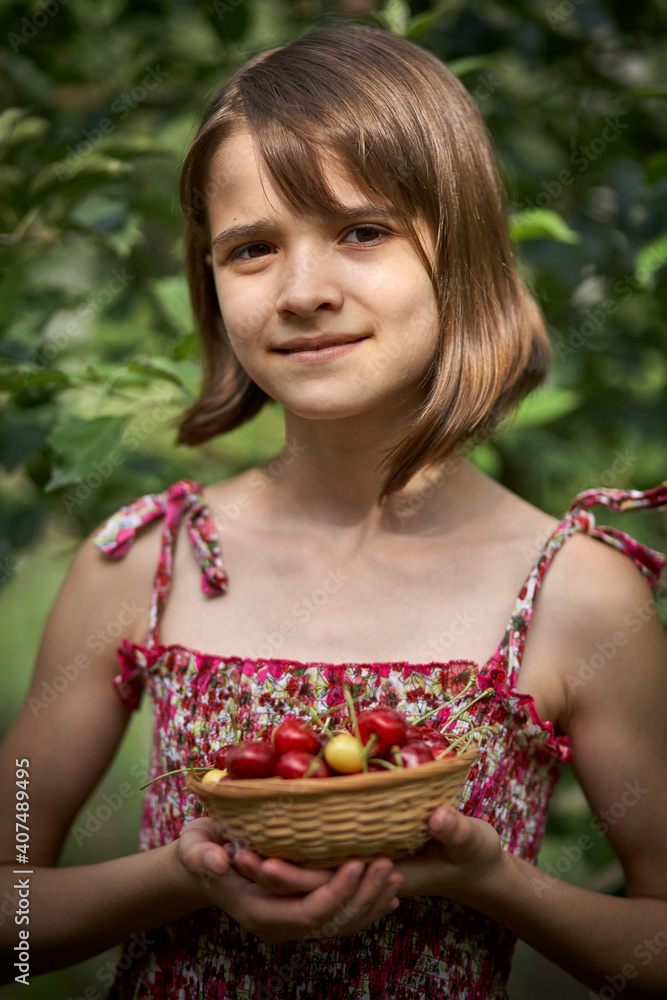 Beautiful girl holding a bowl of cherries in the garden