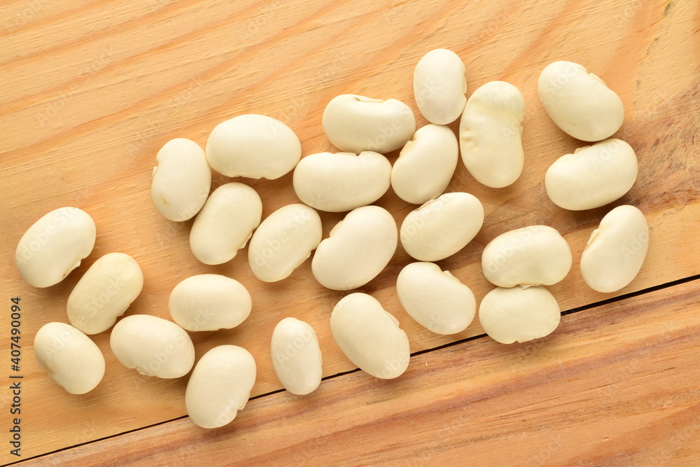 Several grains of dried white beans, close-up, on a wooden table.