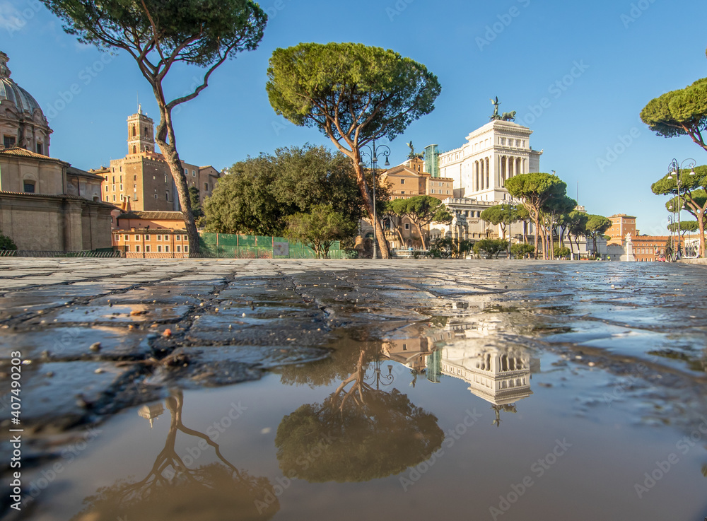 Rome, Italy - in Winter time, frequent rain showers create pools in which the wonderful Old Town of Rome reflect like in a mirror. Here in particular Via dei Fori Imperiali