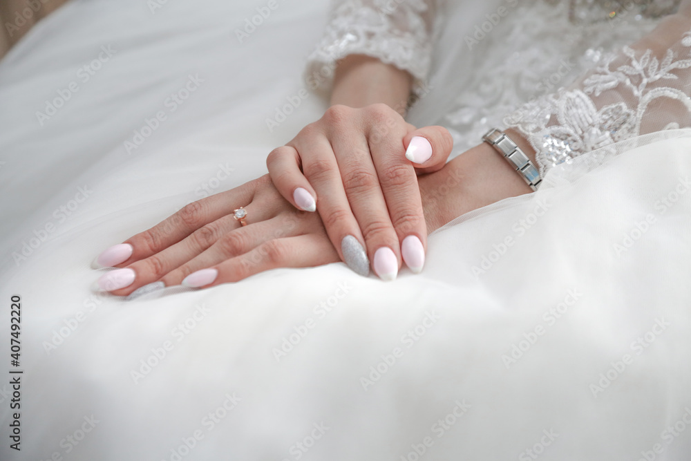 the bride folded her hands with a beautiful manicure on the wedding dress the bride folded her hands with a beautiful manicure on the wedding dress