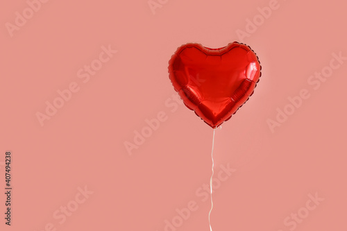 Celebrating Saint Valentine's Day with heart shaped red foil air balloon. Gift for loved woman on special occasion with romantic symbols, Women's day. Close up, copy space, background, isolated.
