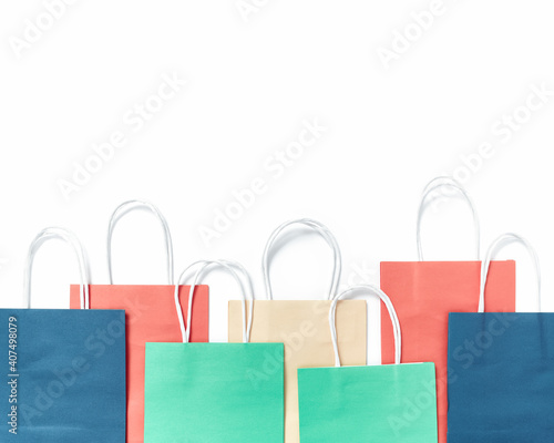 Multicolored blank folded paper shopping bags are on a white background. Flat lay, top view, copy space.