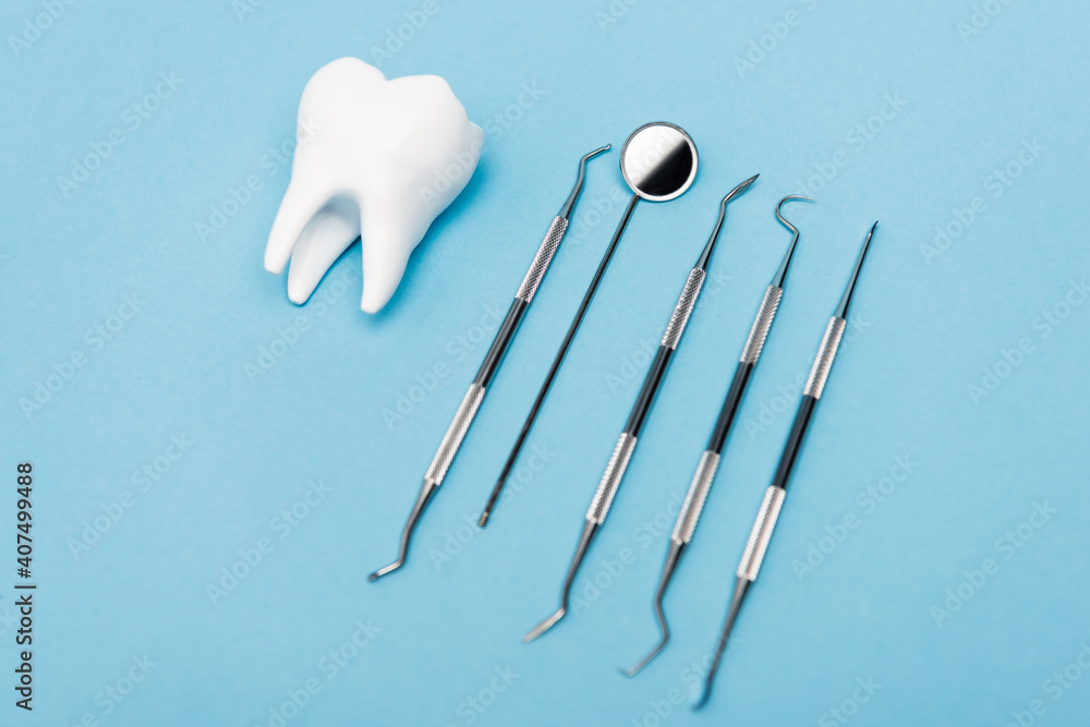 White tooth model and dental tools on blue background White tooth model and dental tools on blue background