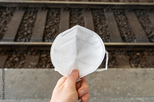 FFP2 certified face mask on a train platform with rails and a track bed in the background. Disposable protection at the train station. photo