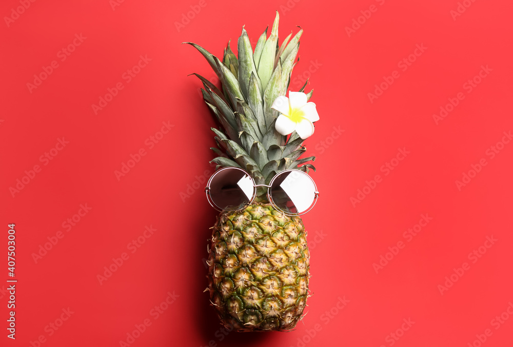 Pineapple with sunglasses and plumeria flower on red background, top view. Creative concept Pineapple with sunglasses and plumeria flower on red background, top view. Creative concept