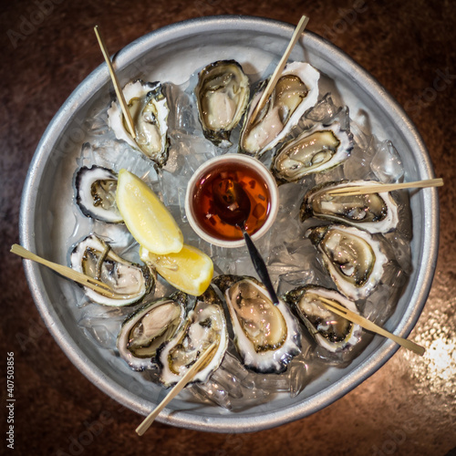 Natural raw oysters with lemon on ice fancy dish with red sauce seafood 