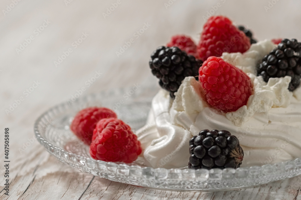 Pavlova's cake, decorated with raspberries and blackberries. Light wooden background. Home cooking. Pavlova's cake, decorated with raspberries and blackberries. Light wooden background. Home cooking.
