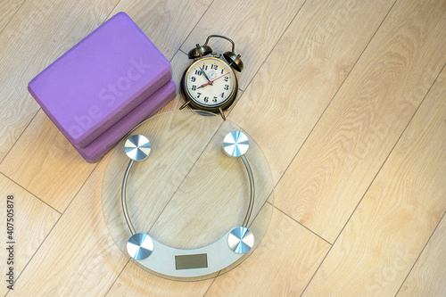 Bathroom scales and alarm clock and yoga bricks. Fitness for weight loss.