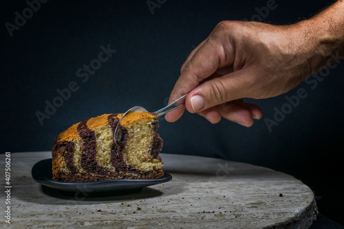 
Delicious vanilla cake with chocolate hand chopping the cake to taste it