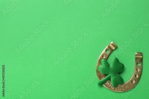 Decorative clover leaf and horseshoe on green background, flat lay with space for text. St. Patrick's Day celebration