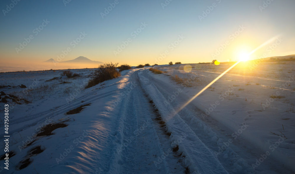 snowy road with mountain at the sunset