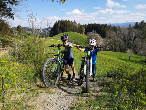 Mädchen und Junge mit Mountain Bike schieben das Rad den Berg hoch.