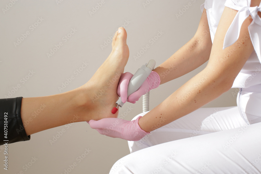 Master in pink gloves makes pedicure on a woman's leg. High quality photo