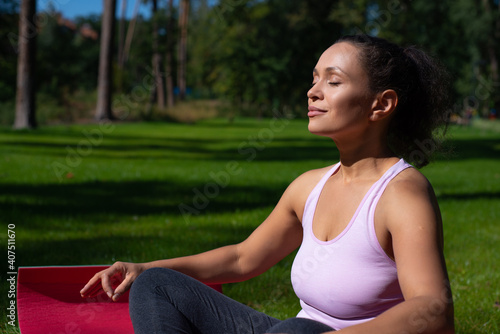 Young woman in lotus position enjoying yoga exercises outdoor