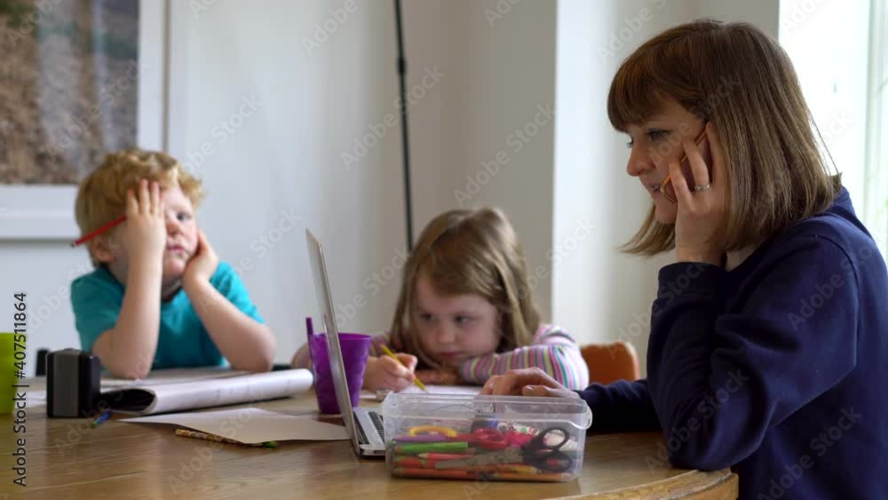 Mum teaching her two kids from home whilst working herself Mum teaching her two kids from home whilst working herself
