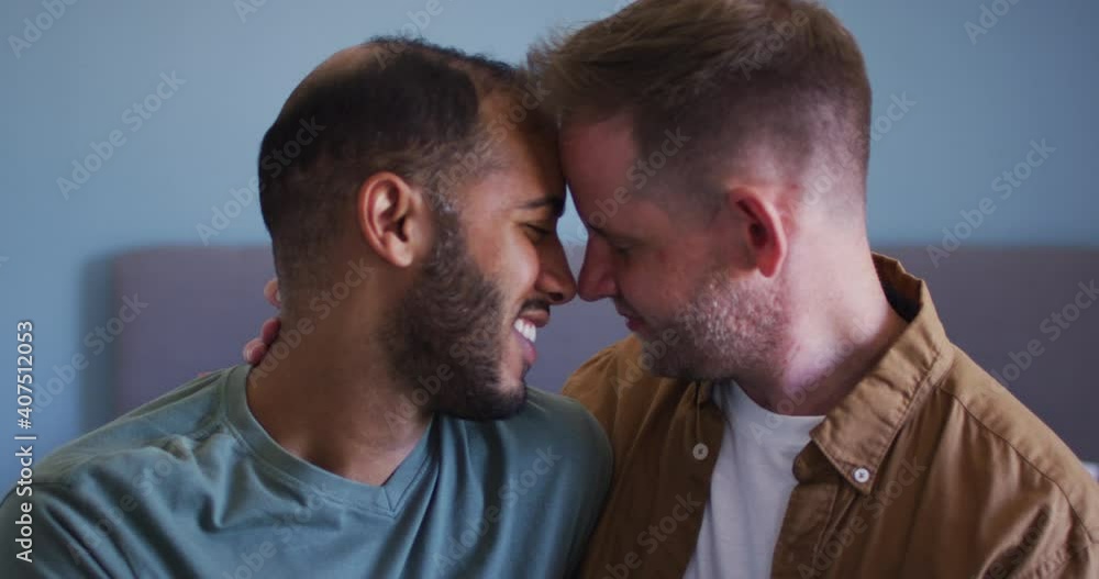 Multi ethnic gay male couple embracing and smiling Multi ethnic gay male couple embracing and smiling