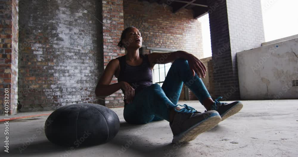 African american man sitting resting after exercising with medicine ball in an empty urban building African american man sitting resting after exercising with medicine ball in an empty urban building