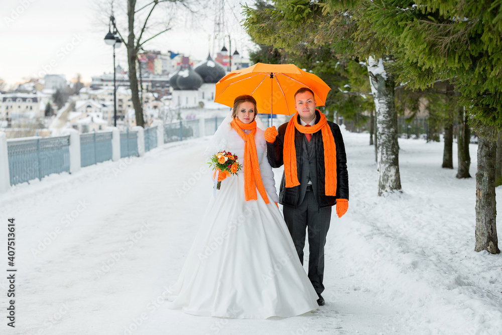 groom and bride on a walk in the city alley under an orange umbrella. Wedding. In the background a church temple
