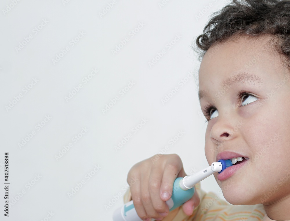boy brushing his teeth with an electric tooth brush on white background stock photo boy brushing his teeth with an electric tooth brush on white background stock photo