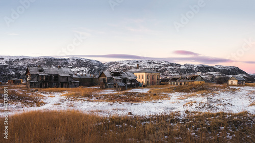 Abandoned houses against the Arctic sky. Old authentic village of Teriberka. Kola Peninsula. Russia.