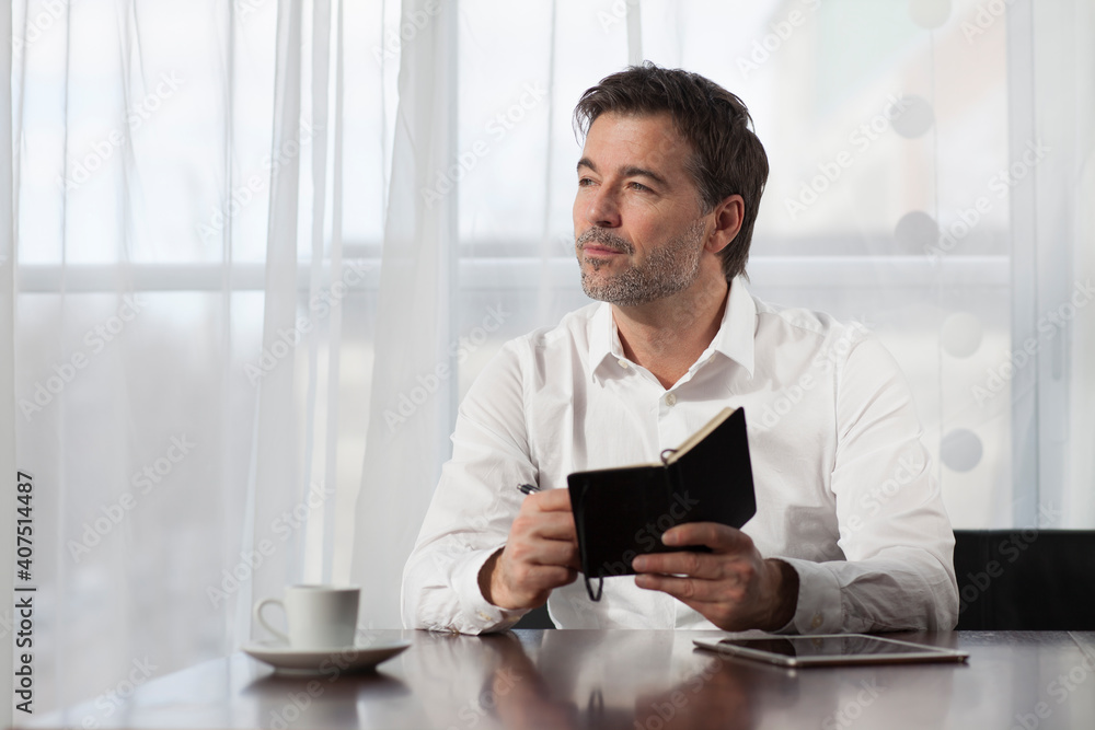 Mature man lost in thought. taking notes in a notebook. Mature man lost in thought. taking notes in a notebook.