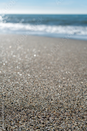 Close up of sand grains on a beach with blurred coastline and horizon in background