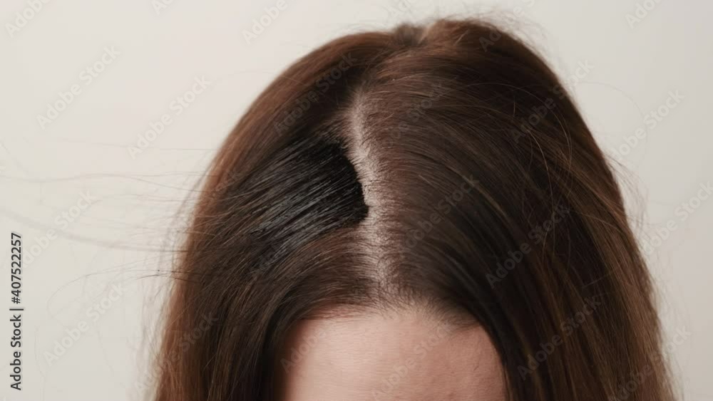 Woman coloring gray hair roots using a brush. Hair dyeing tips at home Woman coloring gray hair roots using a brush. Hair dyeing tips at home