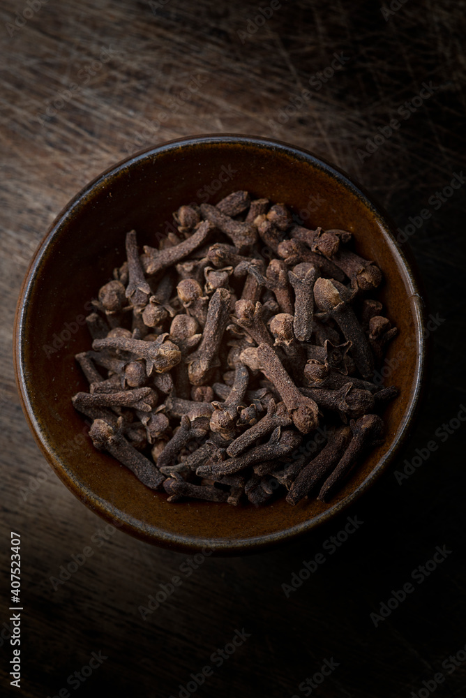 Cloves in a brown bowl on wooden table Cloves in a brown bowl on wooden table