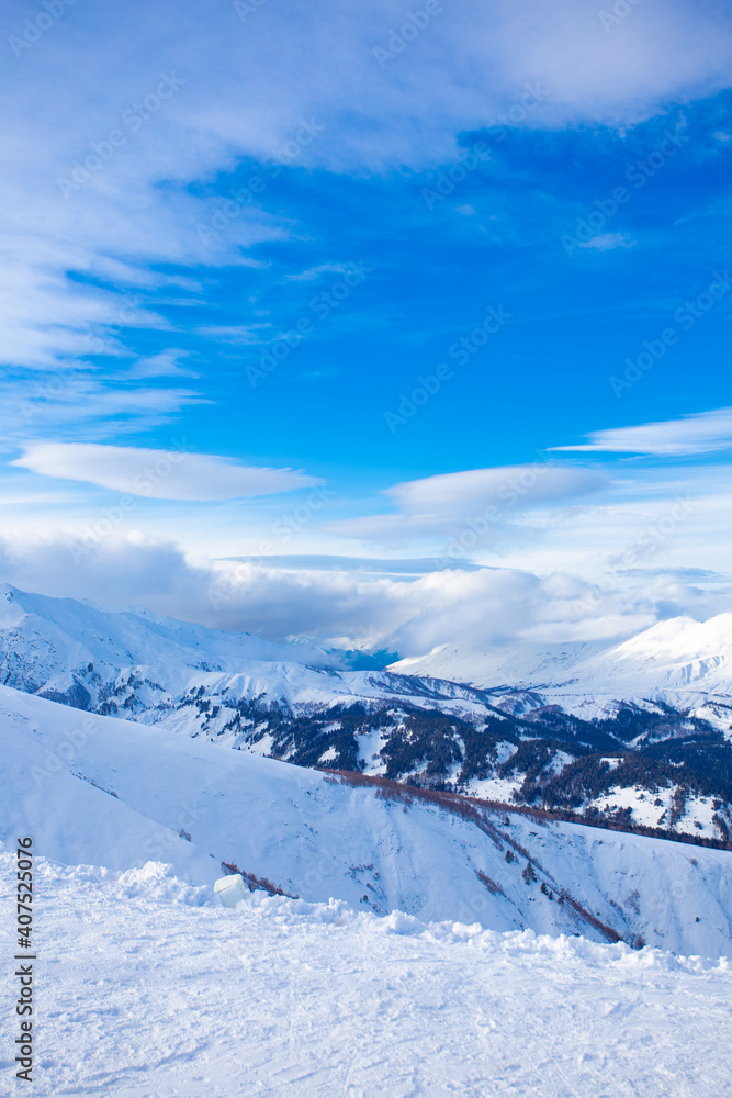 Snow peaks of mountains with blue sky and beautiful clouds. Winter tourism in Russia, Arkhyz. Snow valley on horisontal landscape.