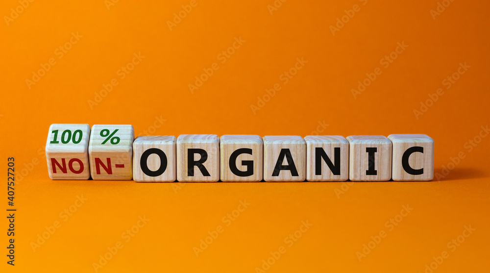 100 percent organic symbol. Fliped wooden cubes and changed words non-organic to 100 percent organic. Beautiful orange background, copy space. Business, healthy lifestyle 100 percent organic concept. 100 percent organic symbol. Fliped wooden cubes and changed words non-organic to 100 percent organic. Beautiful orange background, copy space. Business, healthy lifestyle 100 percent organic concept.