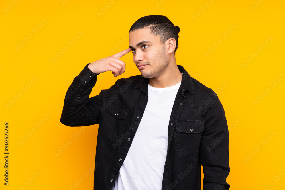 Asian handsome man isolated on yellow background surprised and pointing front Asian handsome man isolated on yellow background surprised and pointing front