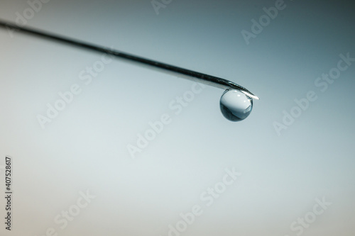 drop of water on the tip of syringe needle, blue background