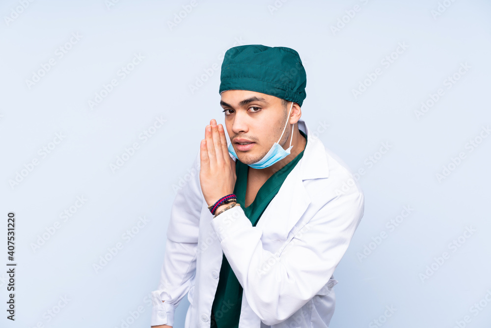 Surgeon man with uniform isolated on blue background whispering something Surgeon man with uniform isolated on blue background whispering something