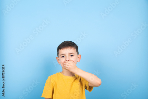 Surprised little boy covered his mouth with his hand