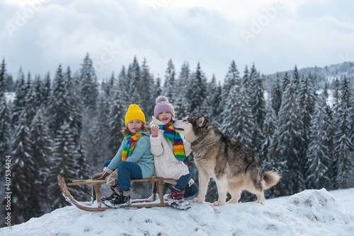 Happy little kids couple with dog haski at the forest nature park in the cold season. Travel children adventure.