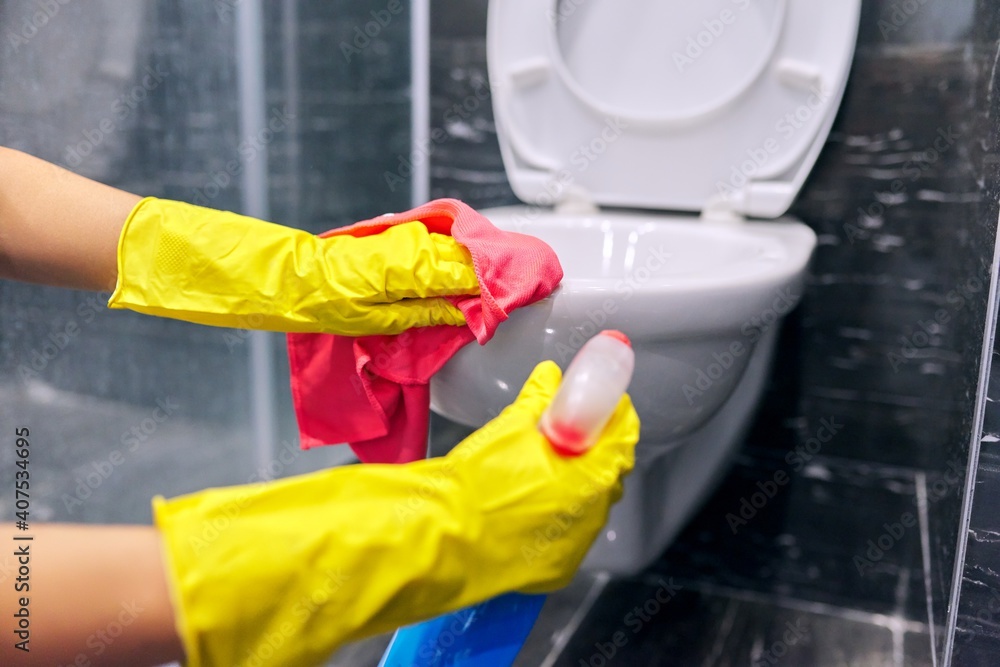 Woman in gloves with detergent washing the toilet close-up Woman in gloves with detergent washing the toilet close-up