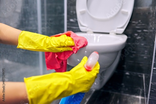 Woman in gloves with detergent washing the toilet close-up