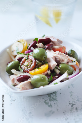 Salad with tuna, green olives and cherry tomatoes. Bright wooden background. Close up.