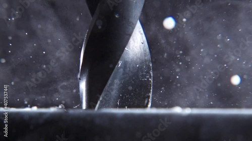 Very close drill drills a sheet metal. Particles are scattered. Slow motion. Very close up drill.