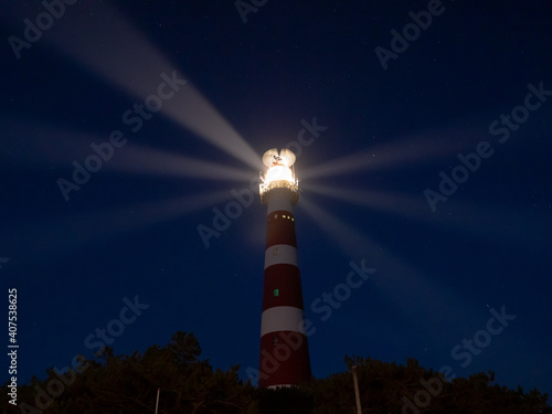 Lighthouse with light rays during night on the island of Ameland, Hollum, Netherlands