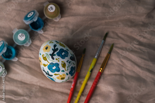 Painted chicken egg in floral pattern. DIY craft for easter holidays with kids. Botanical decoration.Linen natural cloth background. Craft for spring holidays