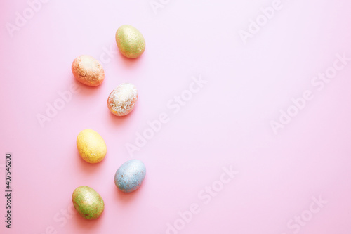 Easter greeting card: colorful golden shiny eggs over pink background