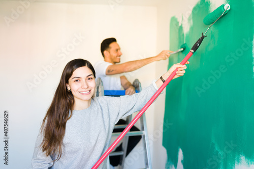Valokuva Young couple applying green paint to their room