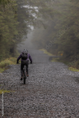 Mountain biker on a forest trail in Glenariff on a wet rainy day, Glenariff forest park, Causeway coast and glens, Glens of Antrim, County Antrim, Northern Ireland