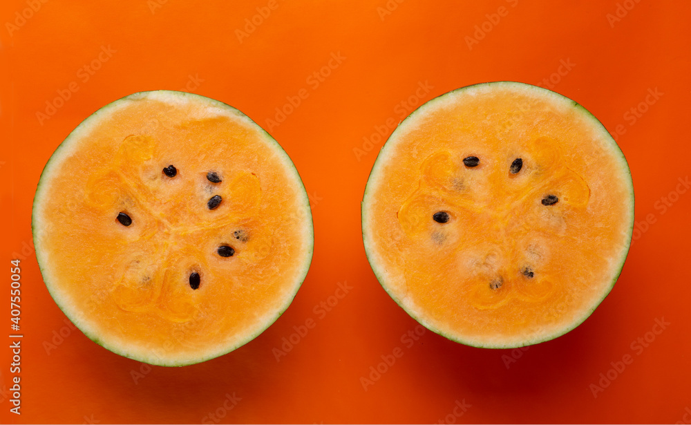 half of fresh ripe orange watermelon around orange background. concept shot half of fresh ripe orange watermelon around orange background. concept shot